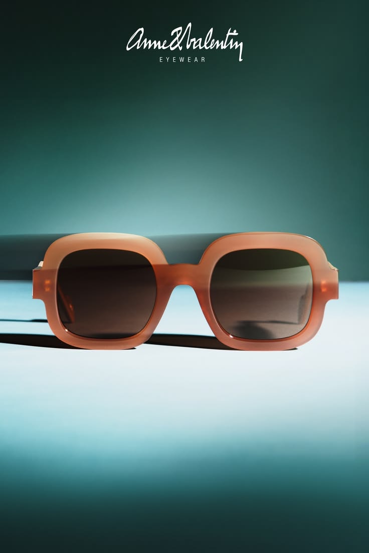 Anne et Valentin rust-colored sculptural acetate sunglasses on a teal background