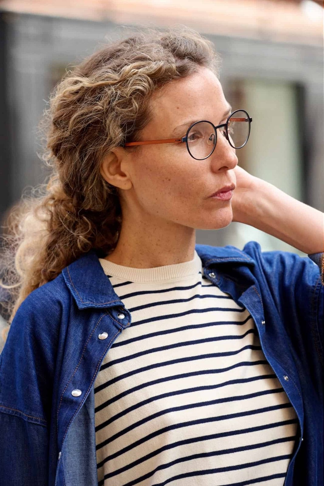 A woman wearing round ProDesign Denmark metal frames, seen from the side in daylight.